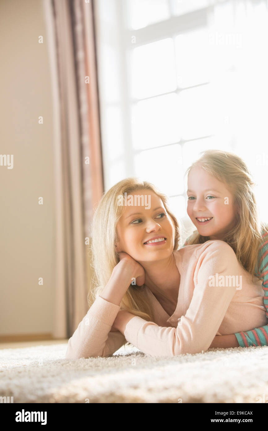 Happy mother and daughter lying on floor at home Stock Photo