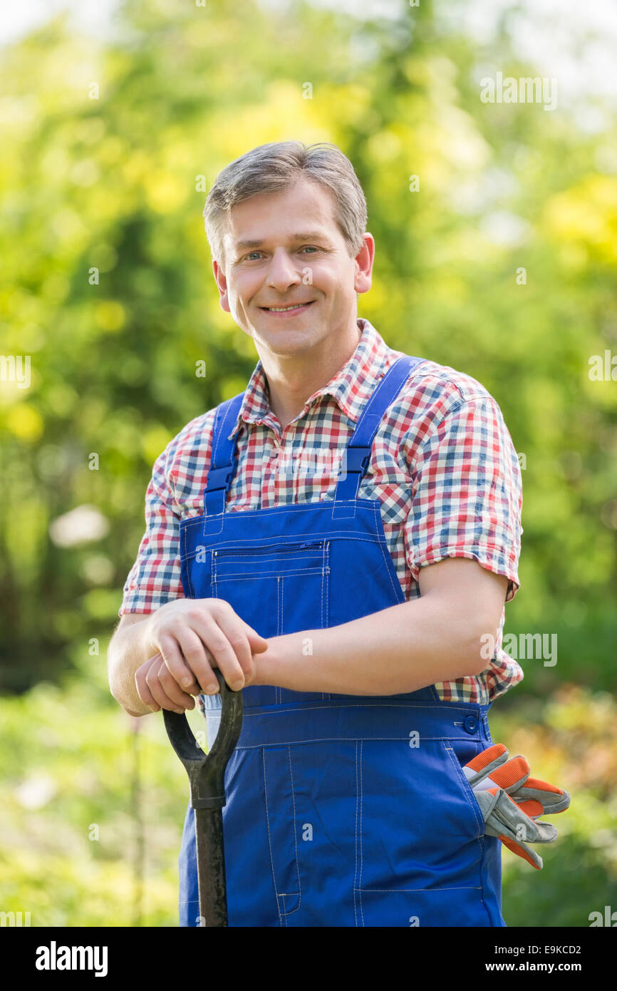 Portrait of happy gardener holding spade in plant nursery Stock Photo ...
