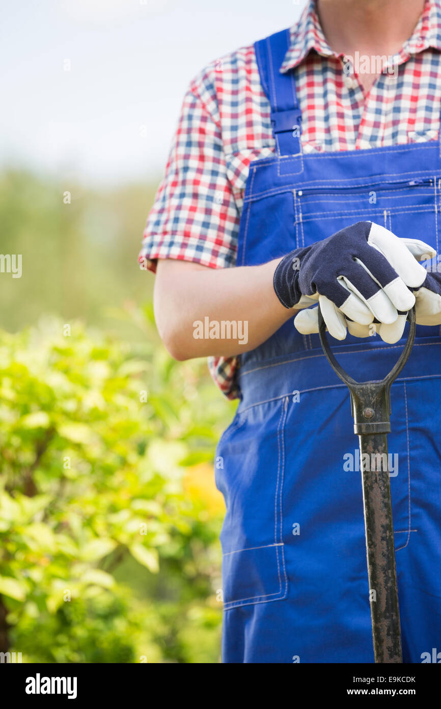 Midsection of man holding spade at garden Stock Photo
