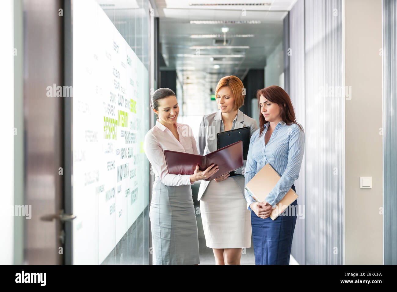 Businesswomen with file folders discussing in office corridor Stock Photo
