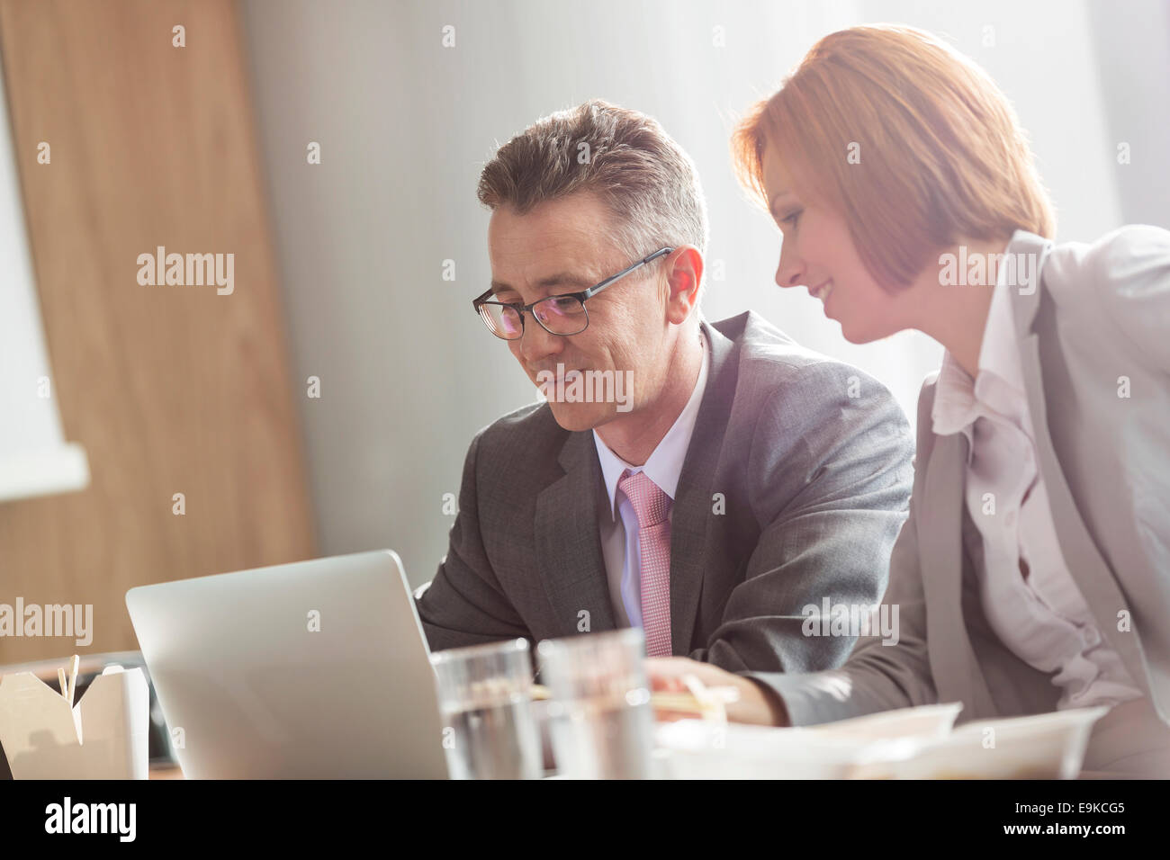 Businessman and businesswoman discussing while having lunch in office Stock Photo