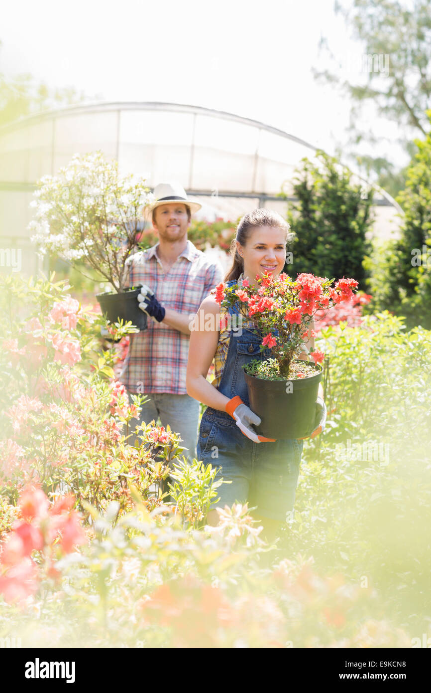 Gardeners holding potted plants outside greenhouse Stock Photo - Alamy