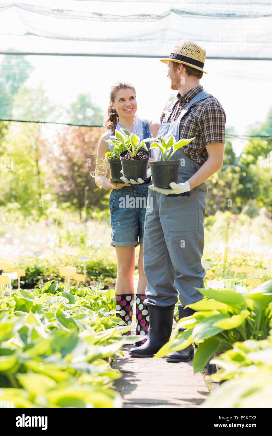 Gardeners discussing while holding potted plants at garden Stock Photo ...