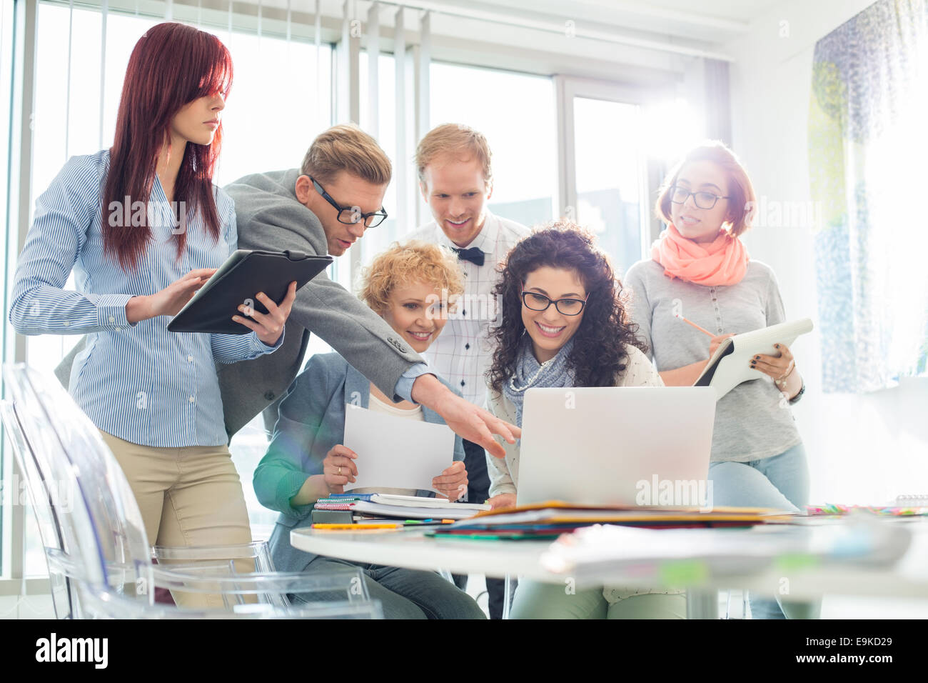 Smiling creative businesspeople working on laptop at desk in office Stock Photo