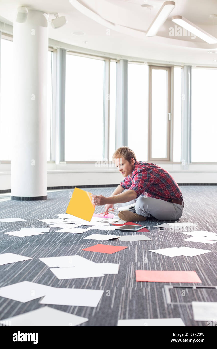Businessman organizing photographs while sitting on floor at creative office Stock Photo