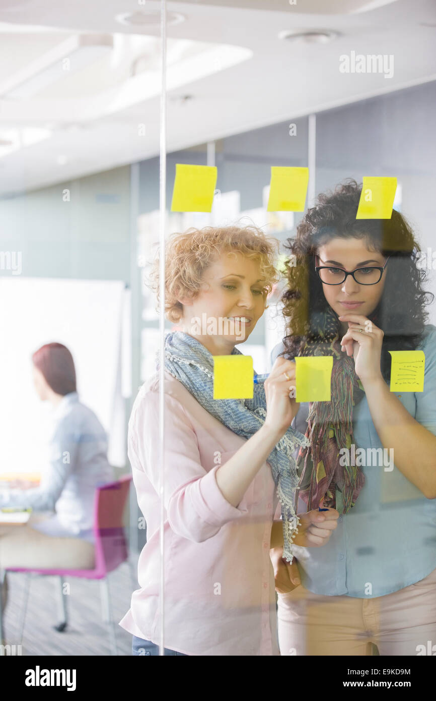 Businesswomen brainstorming with sticky notes in office Stock Photo