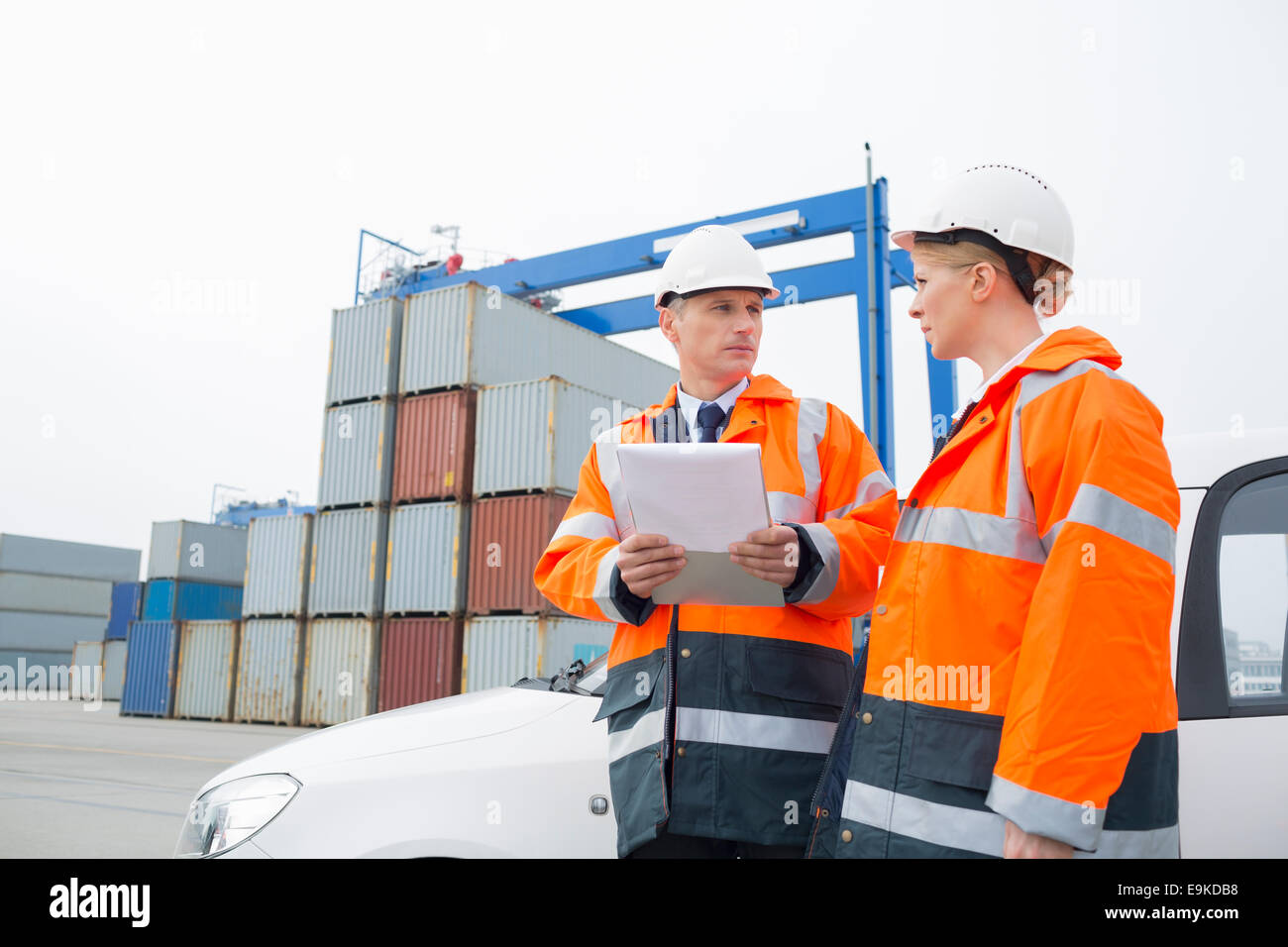 Workers conversing in shipping yard Stock Photo