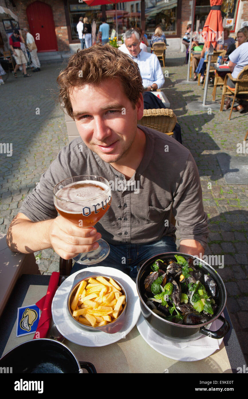 TOURIST EATING MOULES FRITES WITH BELGIAN BEER Stock Photo