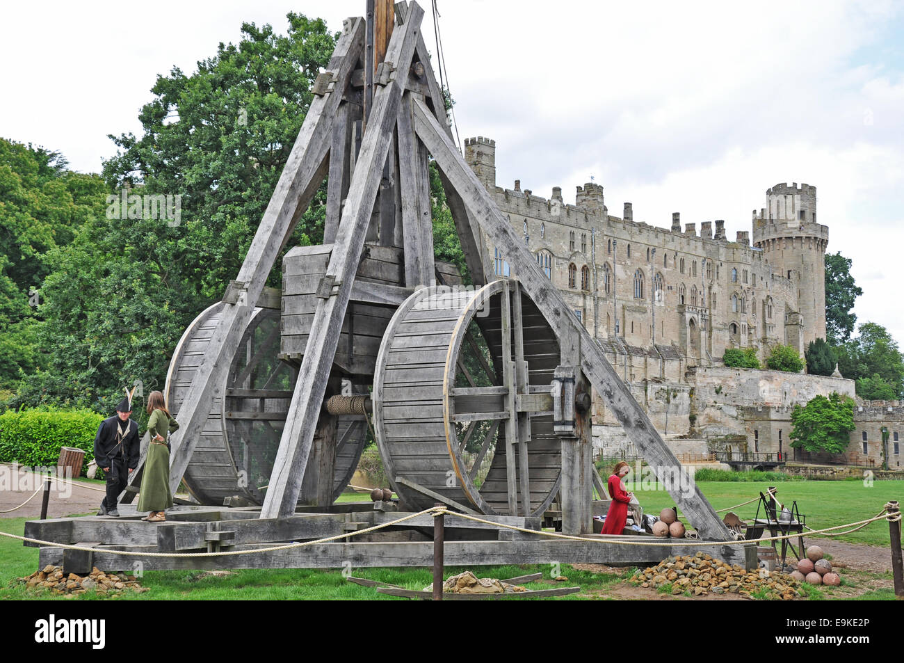 Warwick Castle, England, UK. Man, two women and authentic recreation of a trebuchet (large catapult). World's largest working siege machine. Stock Photo