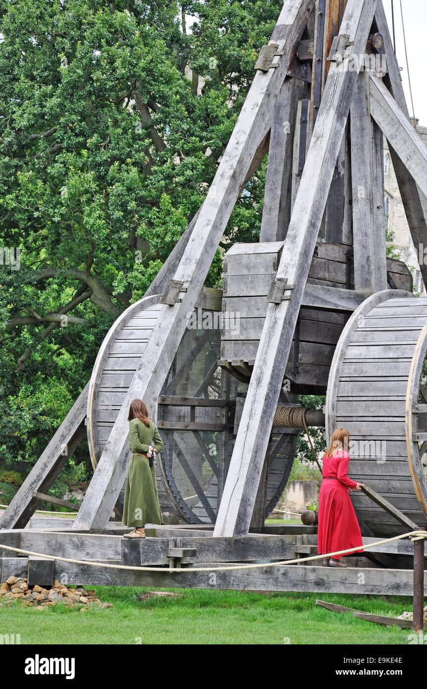 Warwick Castle, England, UK. Two young women and authentic recreation of a trebuchet (large catapult). World's largest working siege machine. Stock Photo