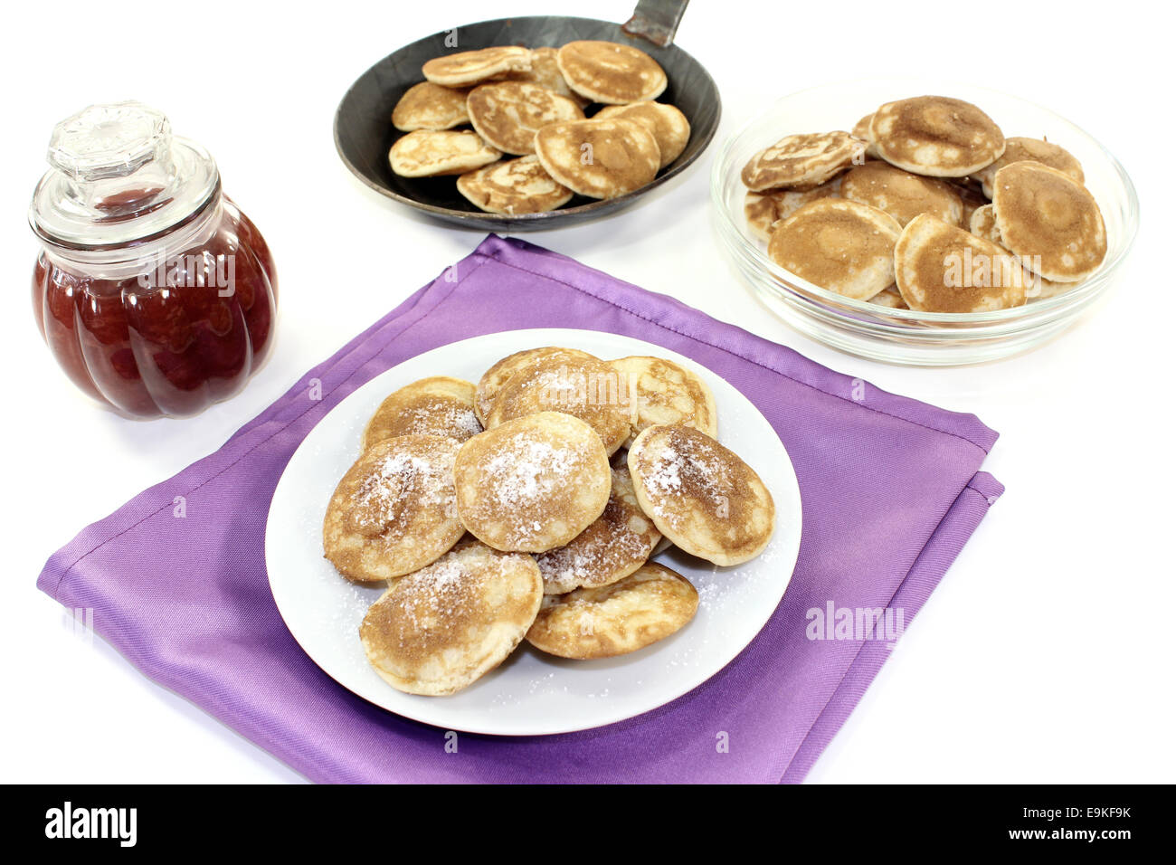 Poffertjes with powdered sugar and fruit jelly on light background