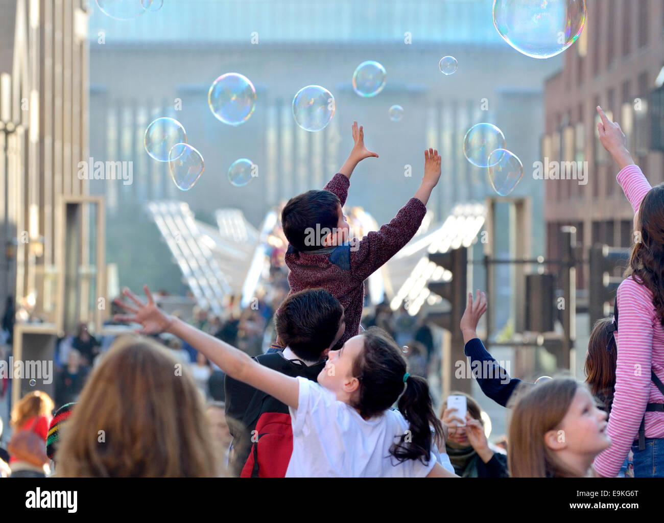 London, England, UK. Children playing with bubbles at the end of Millennium Bridge Stock Photo