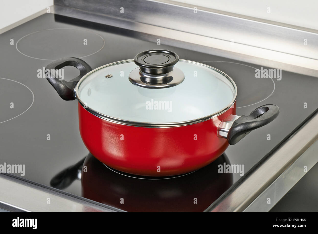 Red ceramic pan with cover on Electric hob in modern and domestic kitchen, view from above Stock Photo
