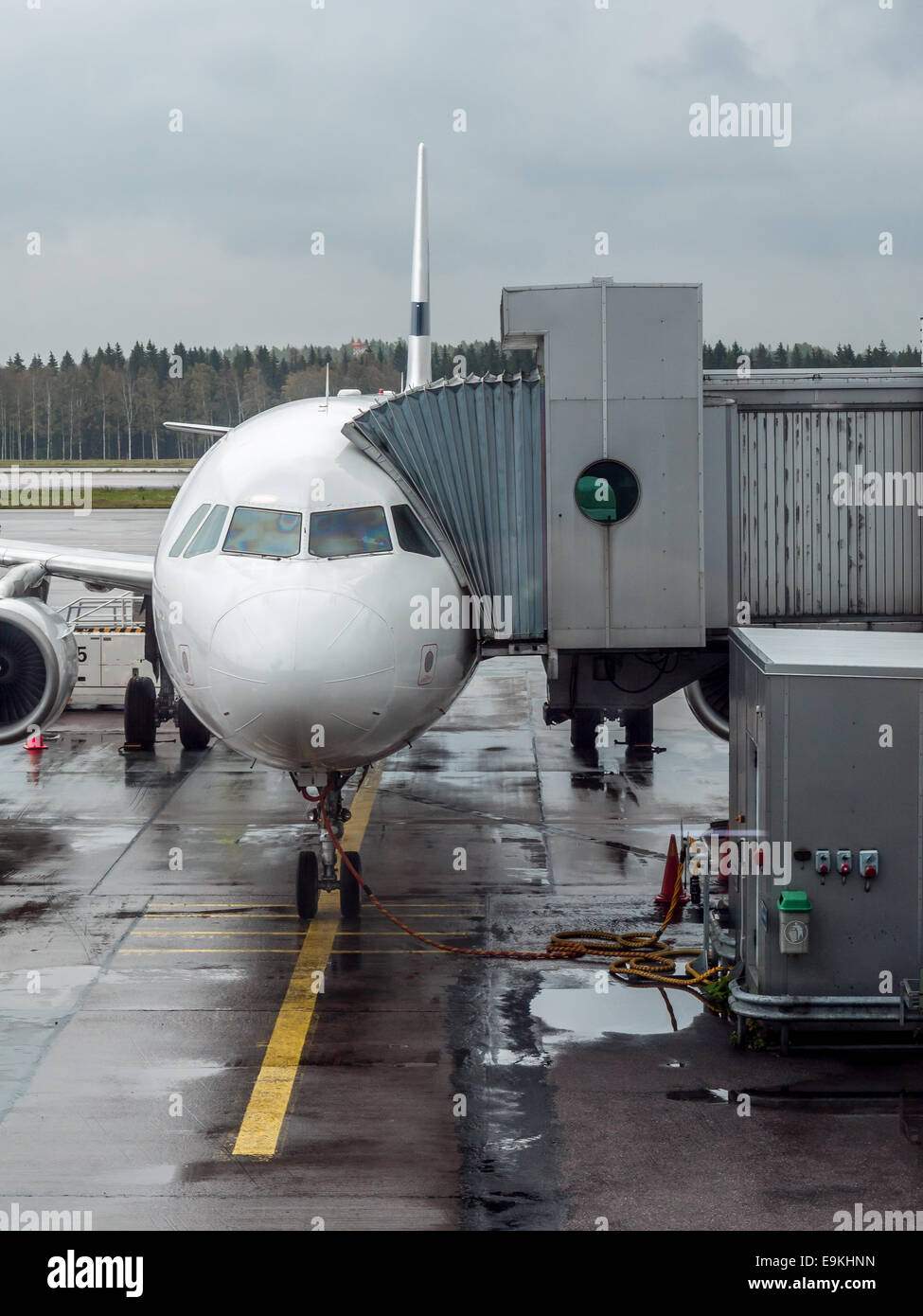 Passenger airplane parked at the airport terminal with telescopic corridor attached while boarding Stock Photo