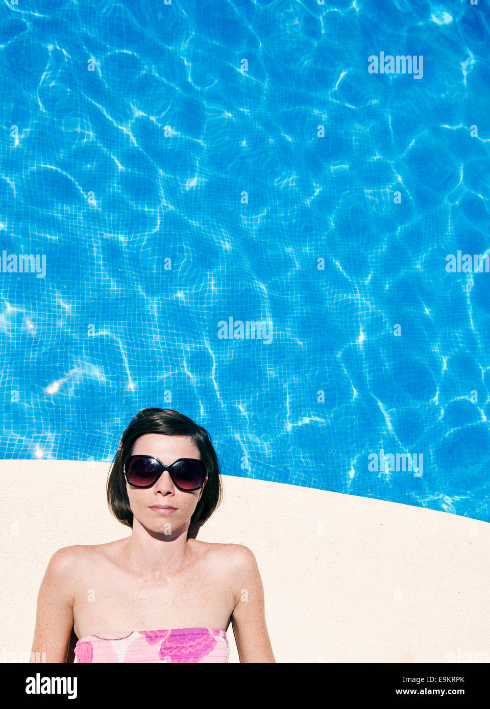 Woman Lying by Swimming Pool Stock Photo