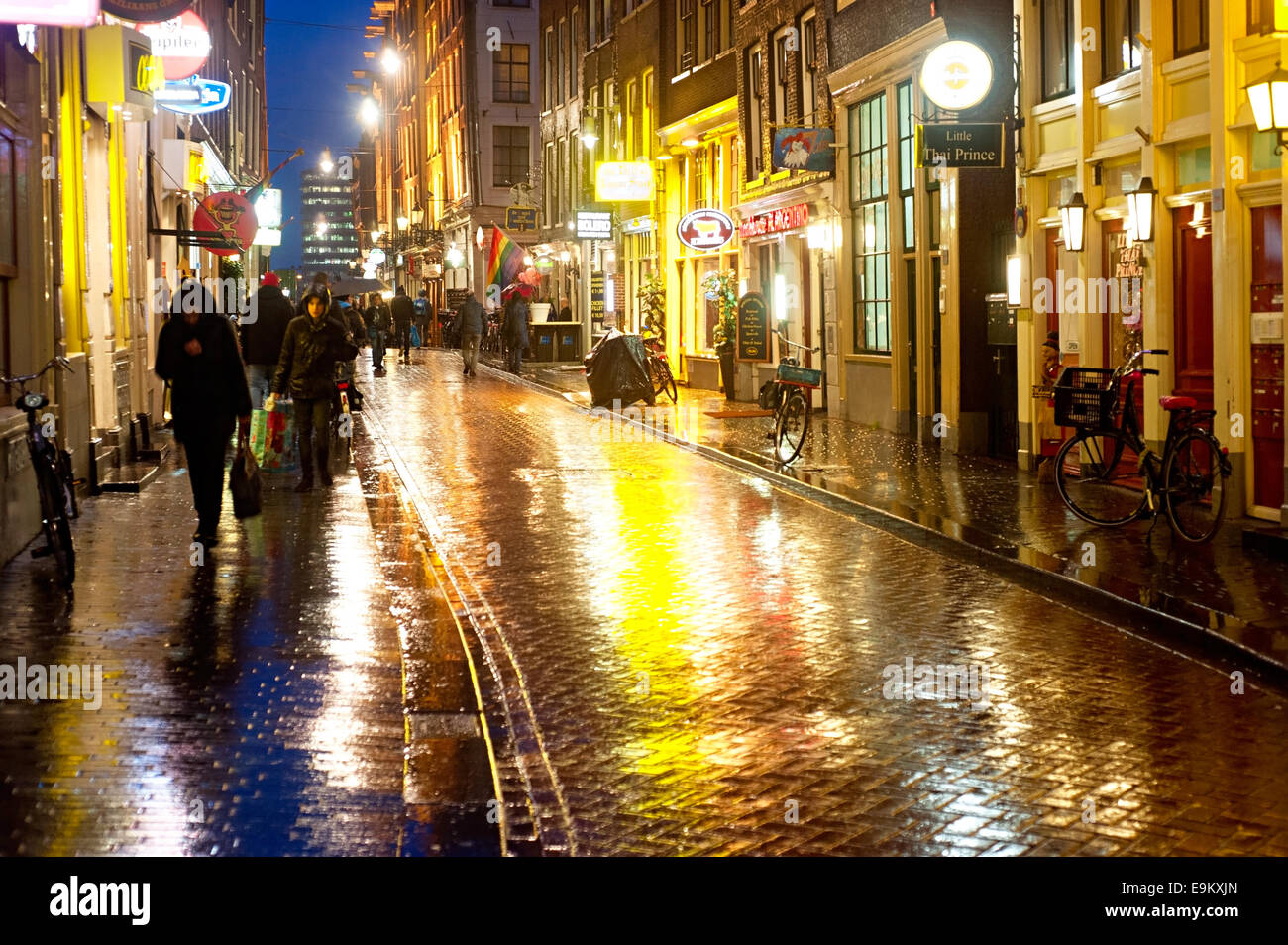 Unidentified people on the street of an old town of Amsterdam in the evening under the rain Stock Photo