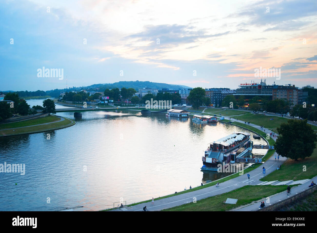 People walking and cycling on the embankment of Vistula river at dusk in Krakow. Stock Photo