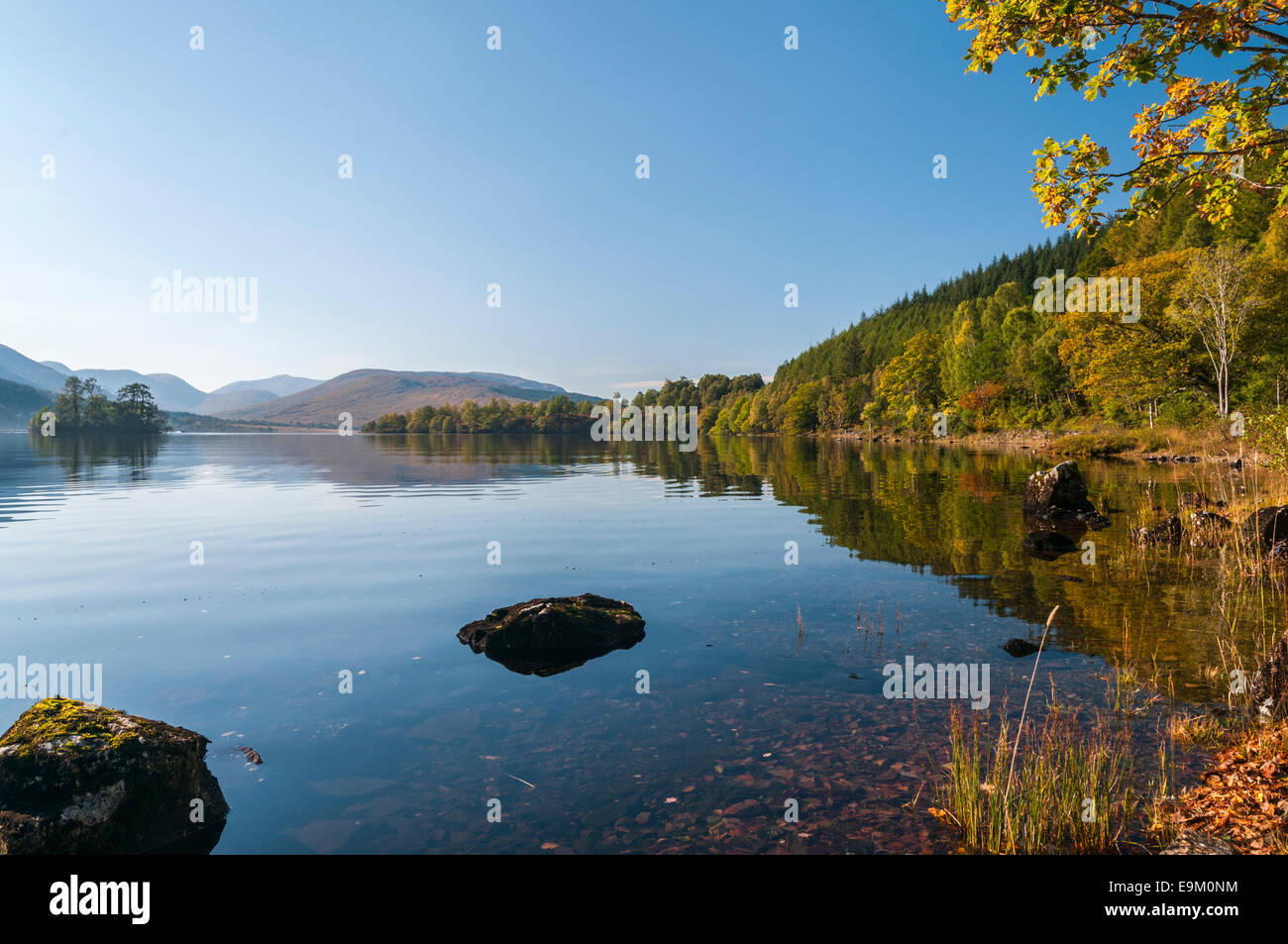 A sunny still autumnal day with the surrounding land and trees reflected in Loch Arkaig, Scotland Stock Photo