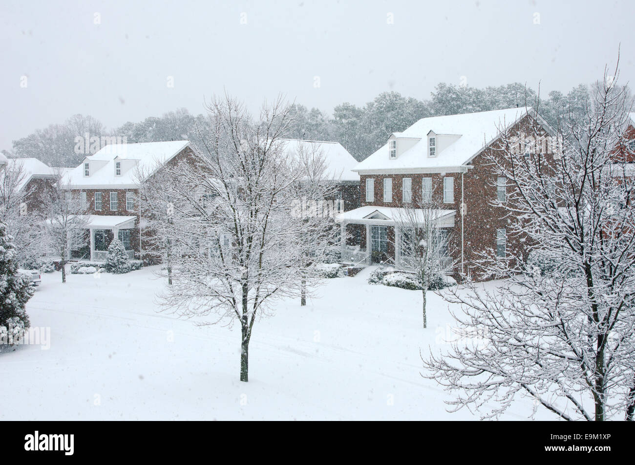 Traditional, brick homes are captured during a snow storm in this beautiful, Winter scene. Stock Photo