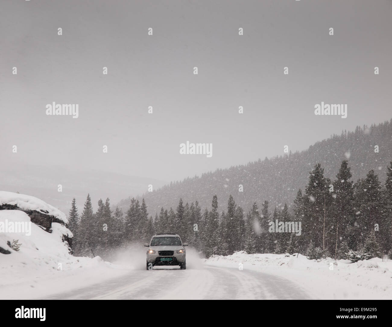 four wheel drive vehicle driving down a snow covered road during a heavy snow storm in the winter. Stock Photo