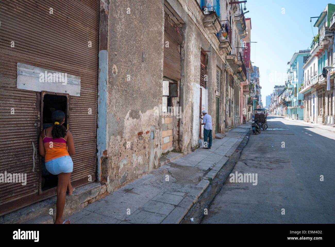 A Cuban woman talking to a neighbor on a street in a rundown section of Central Havana Stock Photo