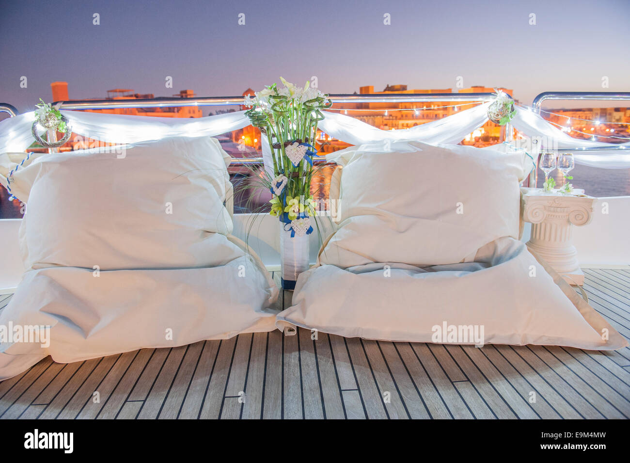 Pair of large white bean bag cushions on deck of boat in marina Stock