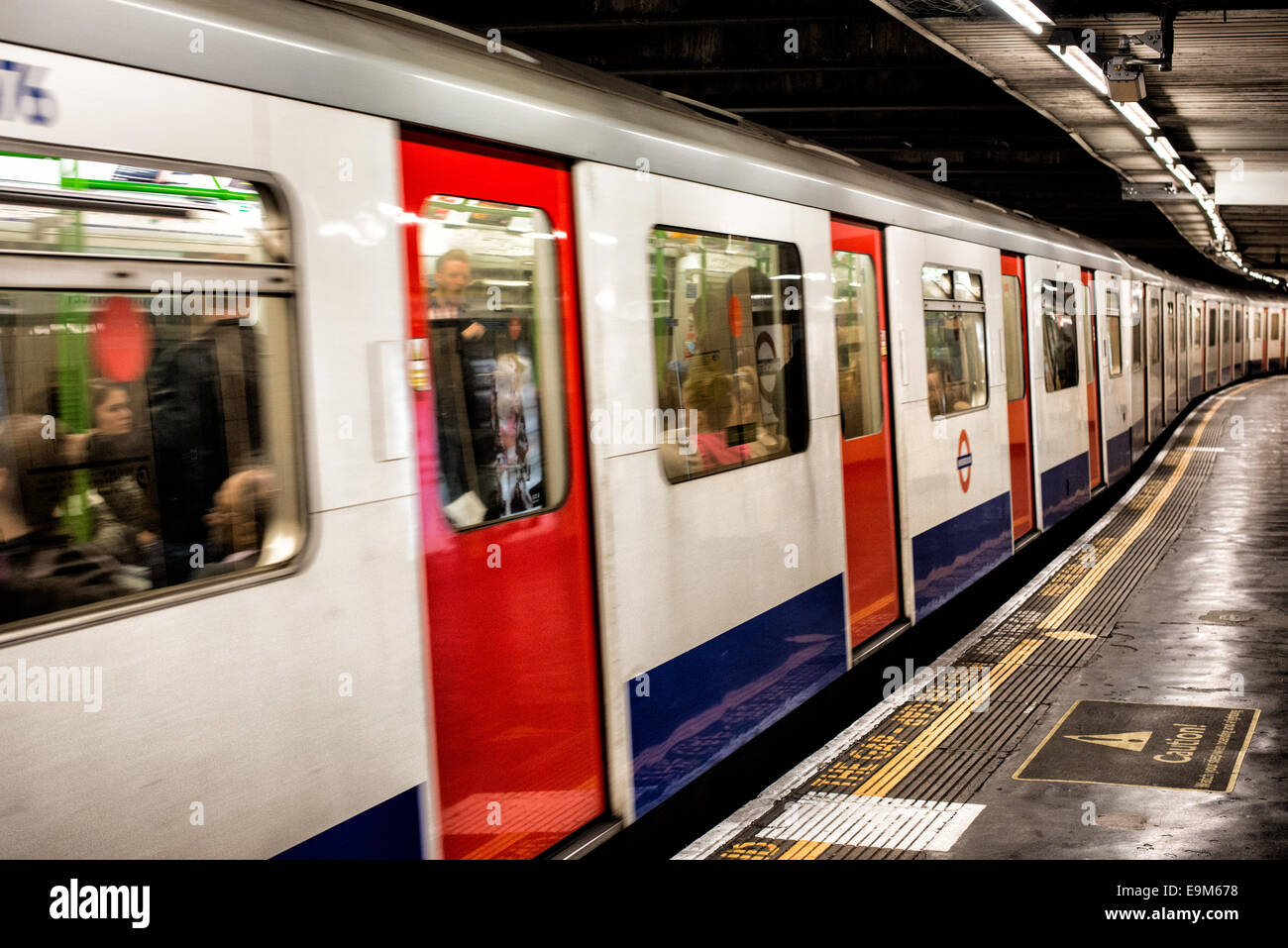 LONDON, United Kingdom — A London Underground train pulls out from a tube stop, departing the platform on the iconic London Tube system. The London Underground, a major part of the city's public transport network, serves millions of passengers daily across Greater London. Stock Photo