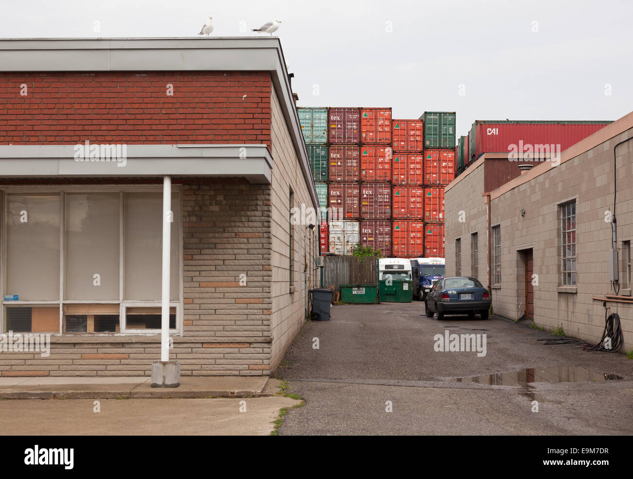 Looking down an industrial laneway with shipping containers in the background. Toronto, Ontario, Canada. Stock Photo