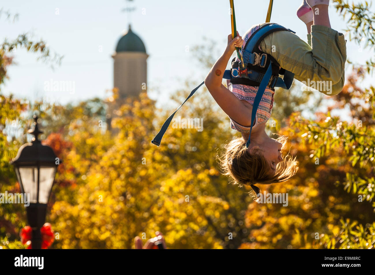 Girl doing somersaults while bouncing on a bungee jump at the Snellville Fall Festival near Atlanta, Georgia, USA. Stock Photo