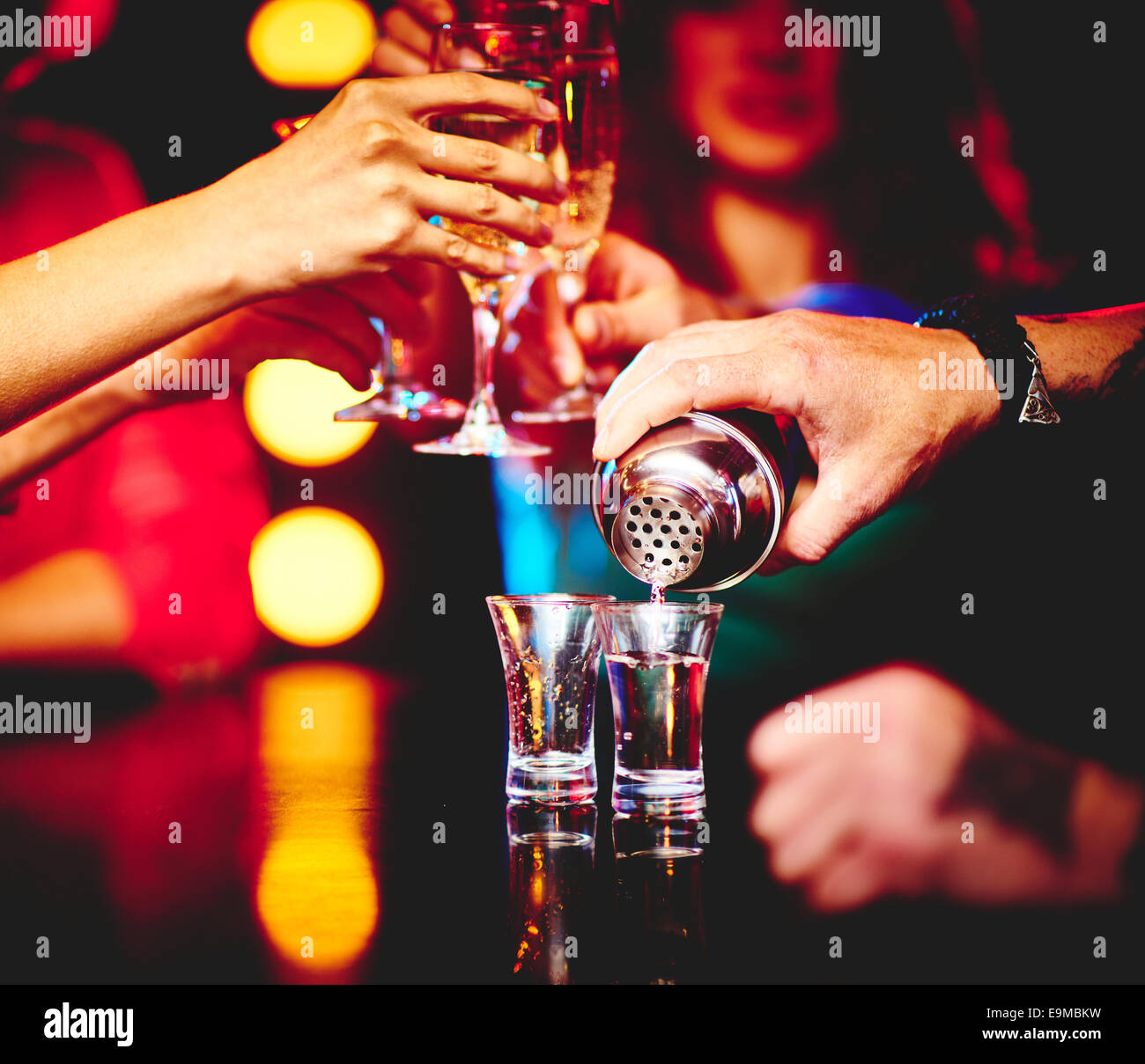 Hand of barman pouring drink into glasses in the bar Stock Photo
