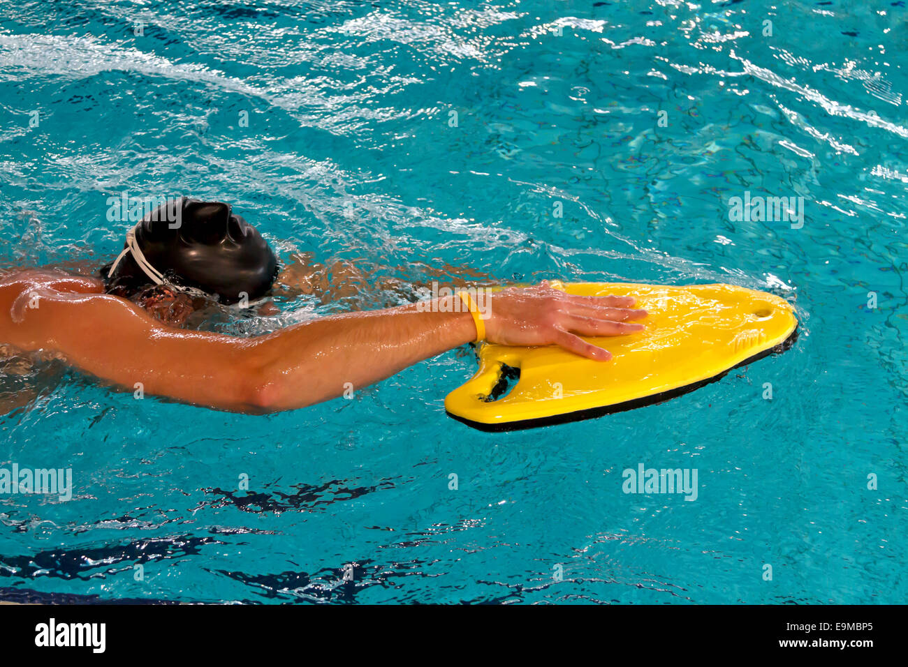 Man practicing swim techniek using a yellow float in swimming pool