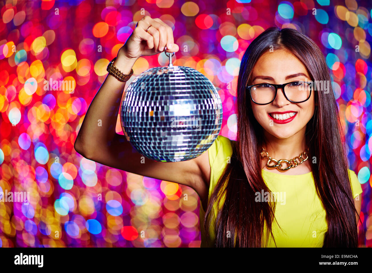 Portrait of glamorous Asian girl with sparkling disco ball looking at
