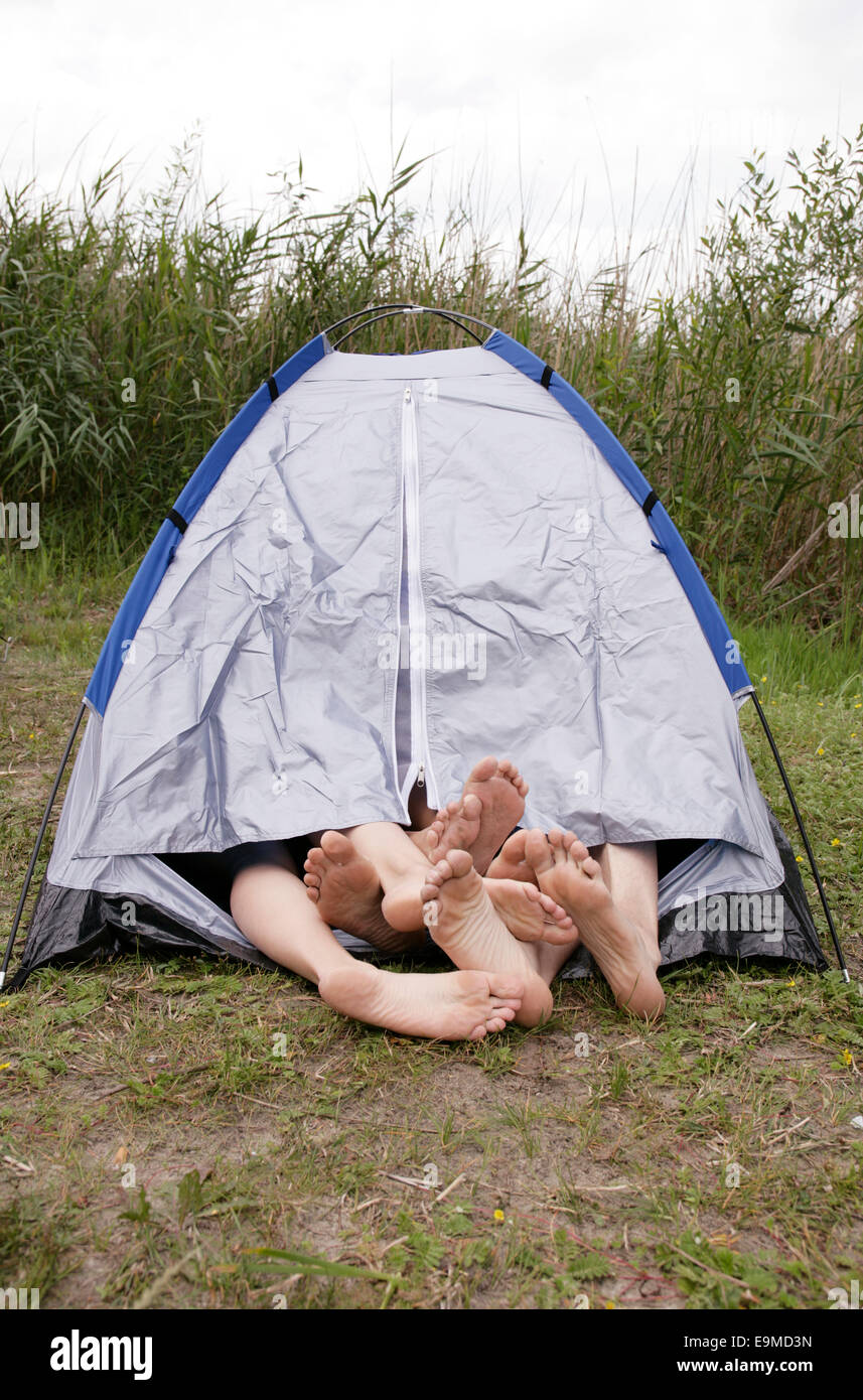 Four barefoot people sharing a tent Stock Photo