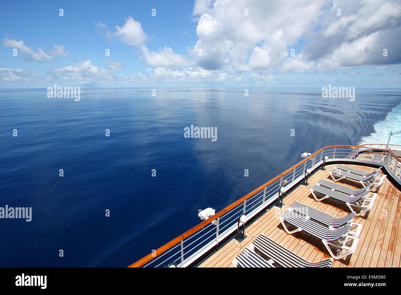 Cruise ship sails across a beautiful calm ocean. Deck chairs are laid out ready for relaxation, Indian Ocean. Stock Photo