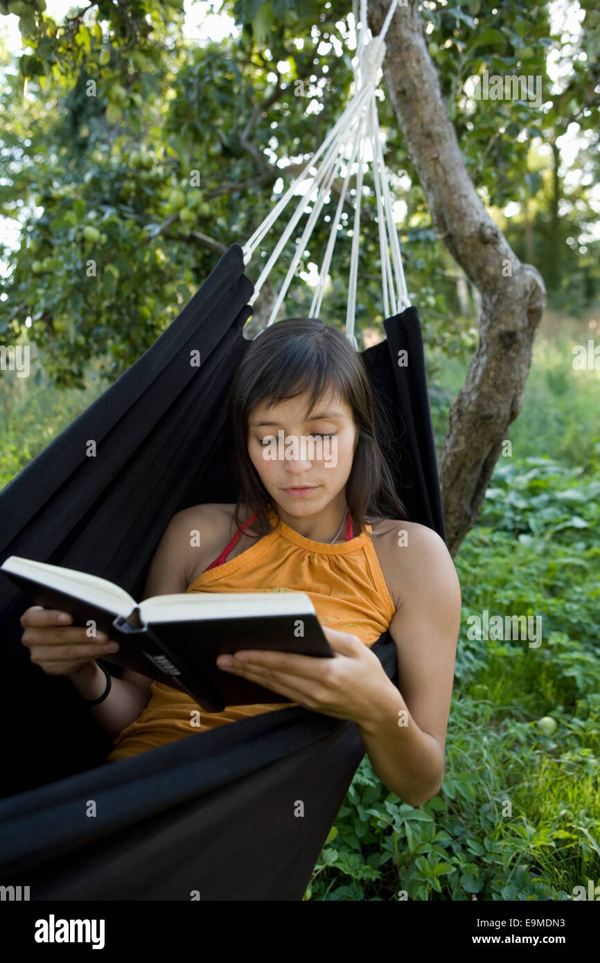 Young woman lying in hammock and reading Stock Photo - Alamy