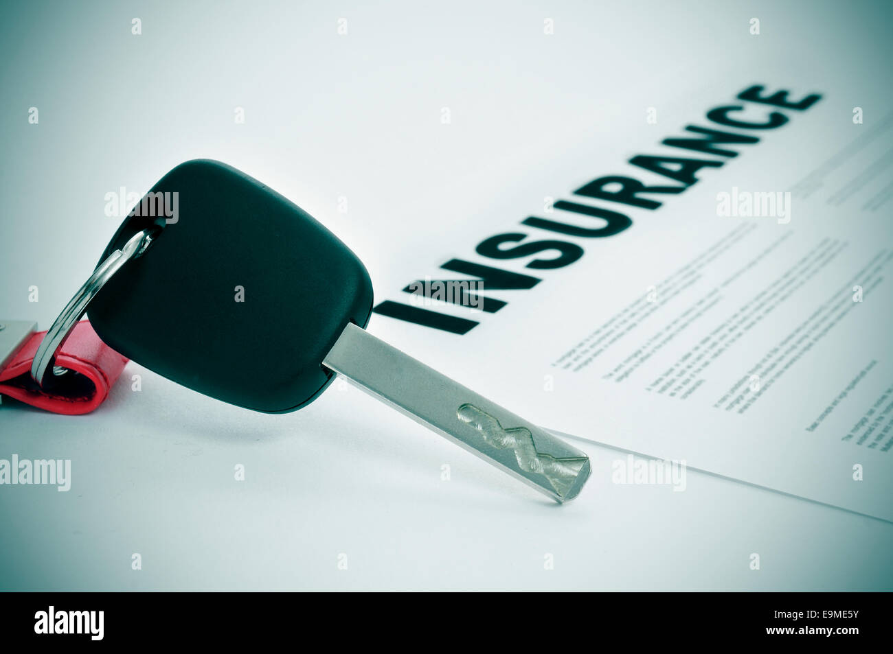 closeup of a car key and a insurance policy on a white surface Stock Photo