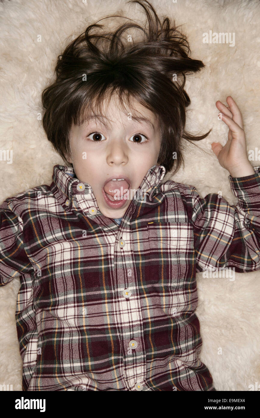 Portrait of shocked boy with mouth open lying on rug Stock Photo