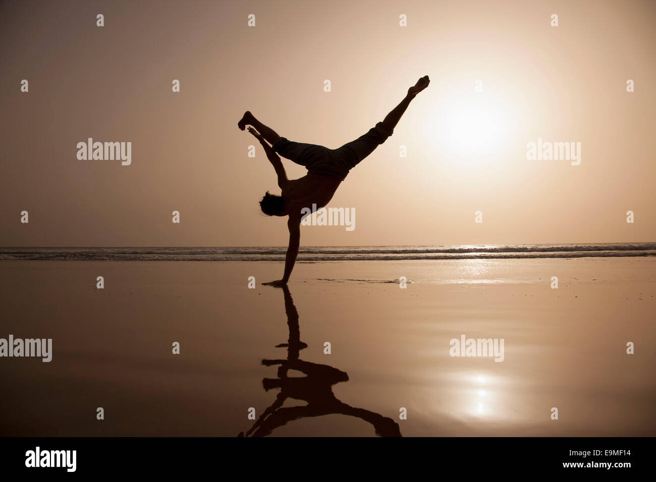 Full length of silhouette man performing handstand at beach Stock Photo