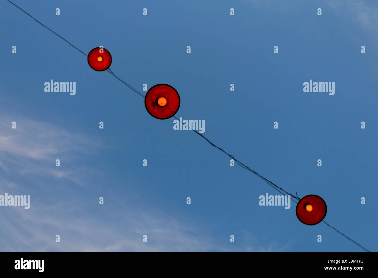 Low angle view of lamps hanging on cable against blue sky Stock Photo