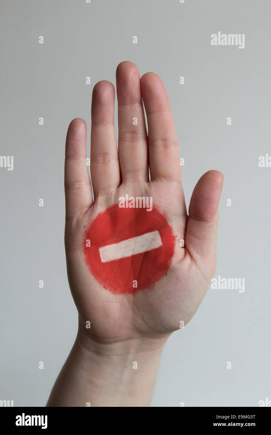 Close-up of stop sign painted on man's hand against gray background Stock Photo