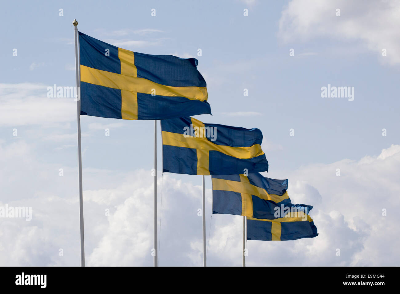 Row of Swedish flag poles against cloudy sky Stock Photo