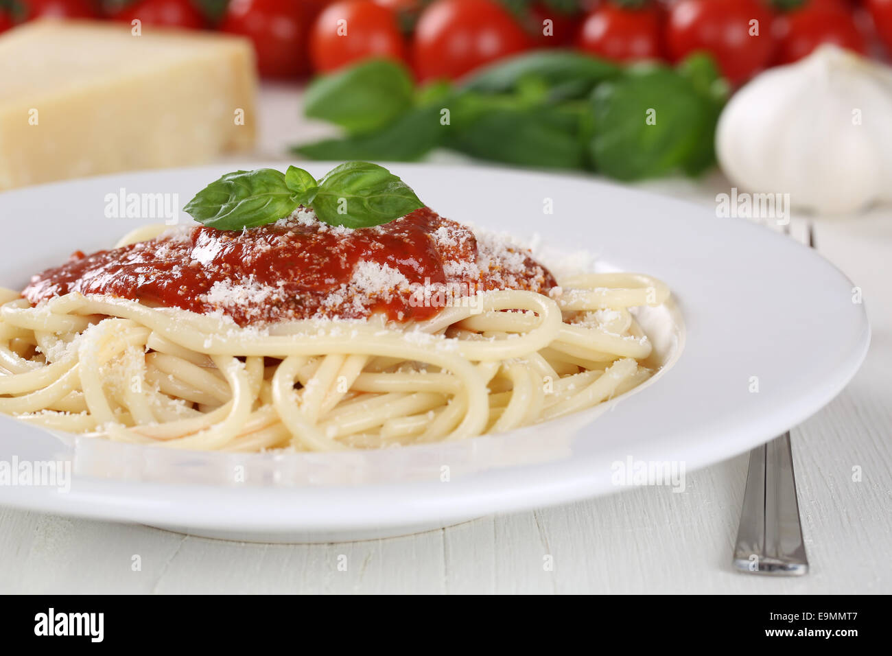 Cooking spaghetti noodles pasta prepared meal with tomato sauce and basil on plate Stock Photo