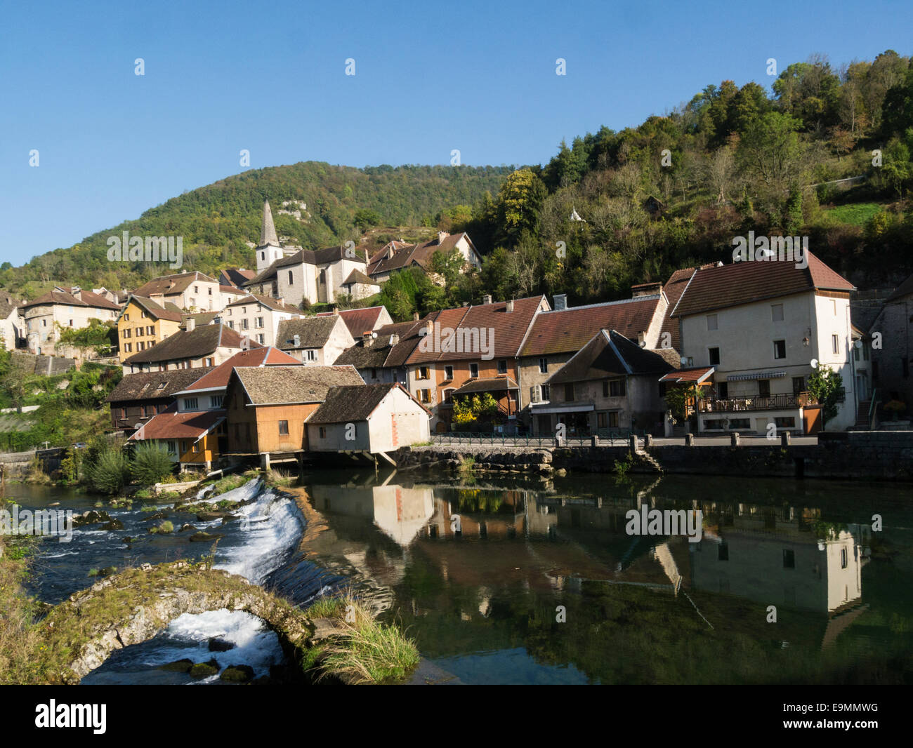 Old buildings in Lods reflected in River Loue old packhorse bridge Eastern France EU Stock Photo