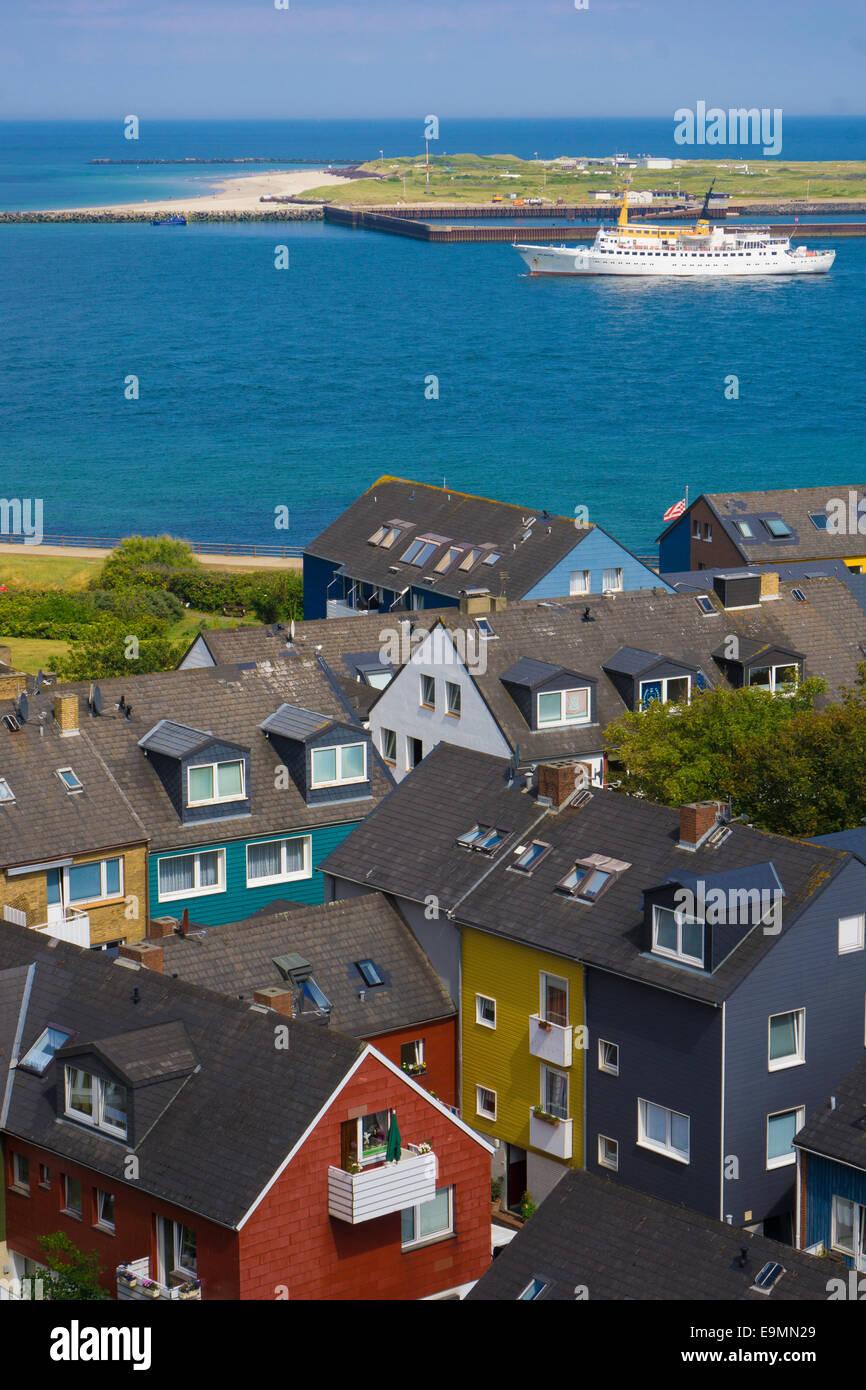 Helgoland Germany colorful houses in town seen from the plateau of the main island toward the island Düne / Dune with ship . Stock Photo