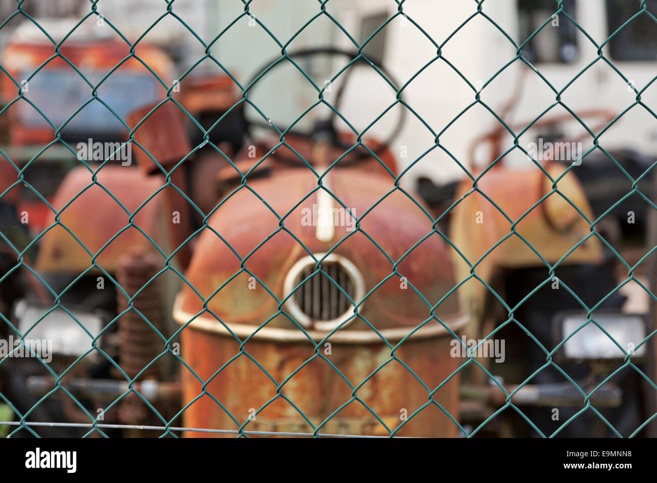Old tractor parked behind wired fencing Stock Photo