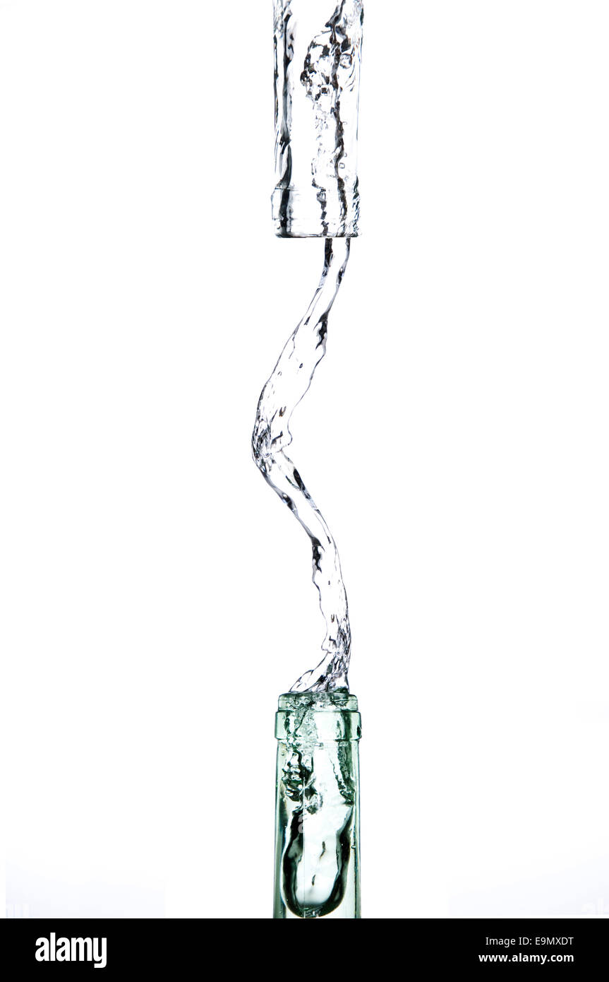 clear water spilled from a glass bottle in front of a white background Stock Photo