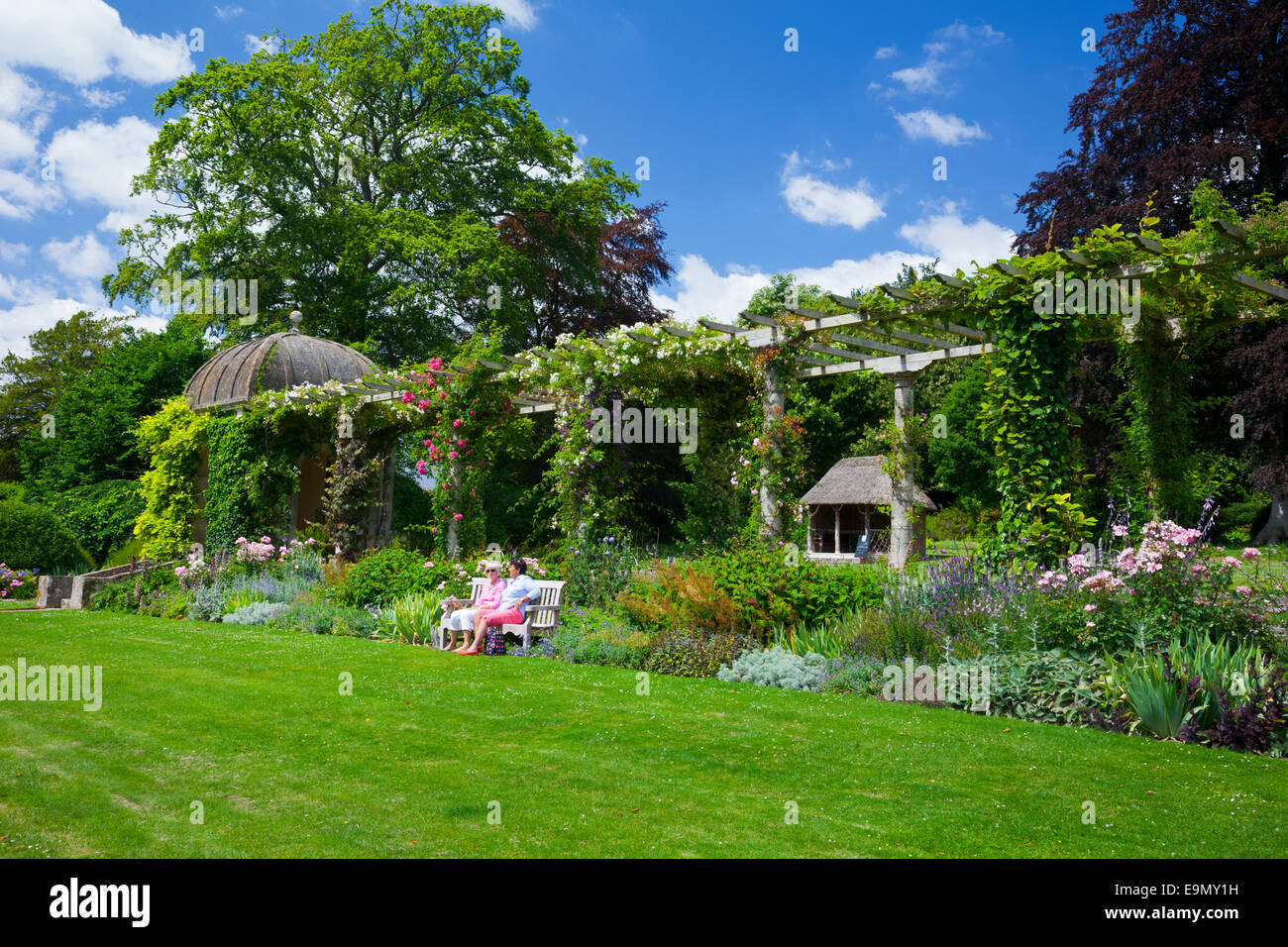 Enjoying the sunshine in front of the 300ft long Edwardian pergola at West Dean Gardens, West Sussex, England, UK Stock Photo