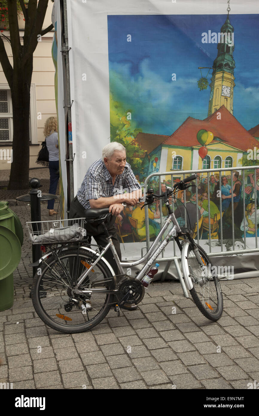 Elderly man rests a moment on his bicycle during a street festival in Zielona Gora, Poland Stock Photo