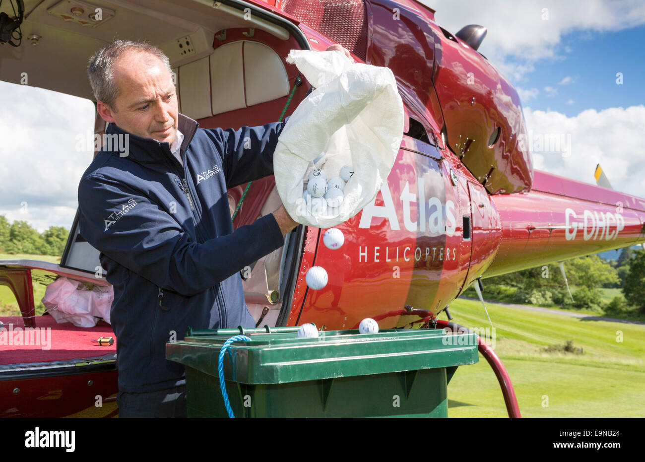 Captain Mike Burns of Atlas Helicopters and colleague Roy Adams prepare their contraption to drop 1,000 golf balls from their Sq Stock Photo