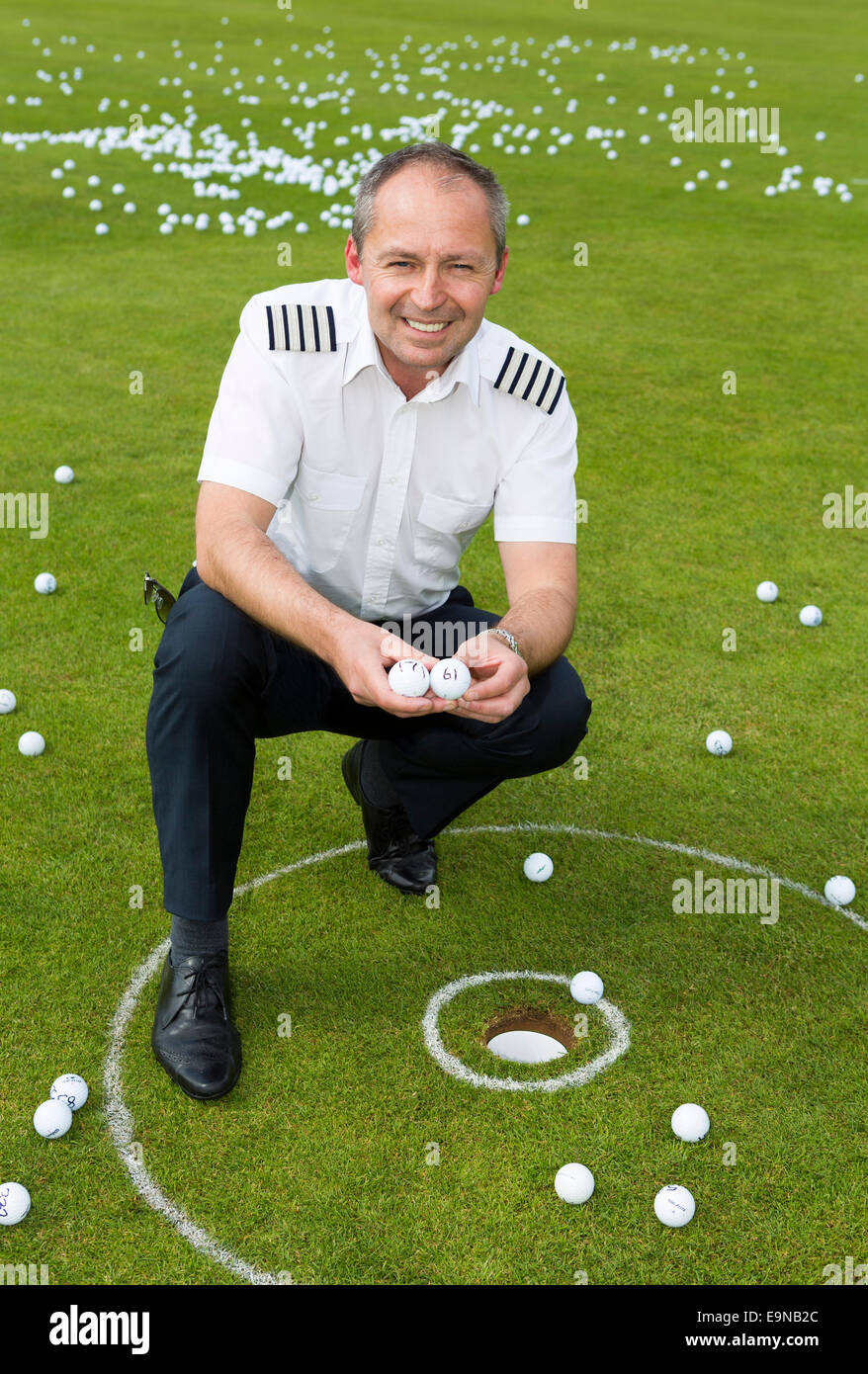 Captain Mike Burns of Atlas Helicopters with two balls which landed in the hole after he dropped 1,000 golf balls from a Squirre Stock Photo